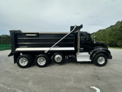 Kenworth T880 dump truck side view showing dump bed and rear wheels.