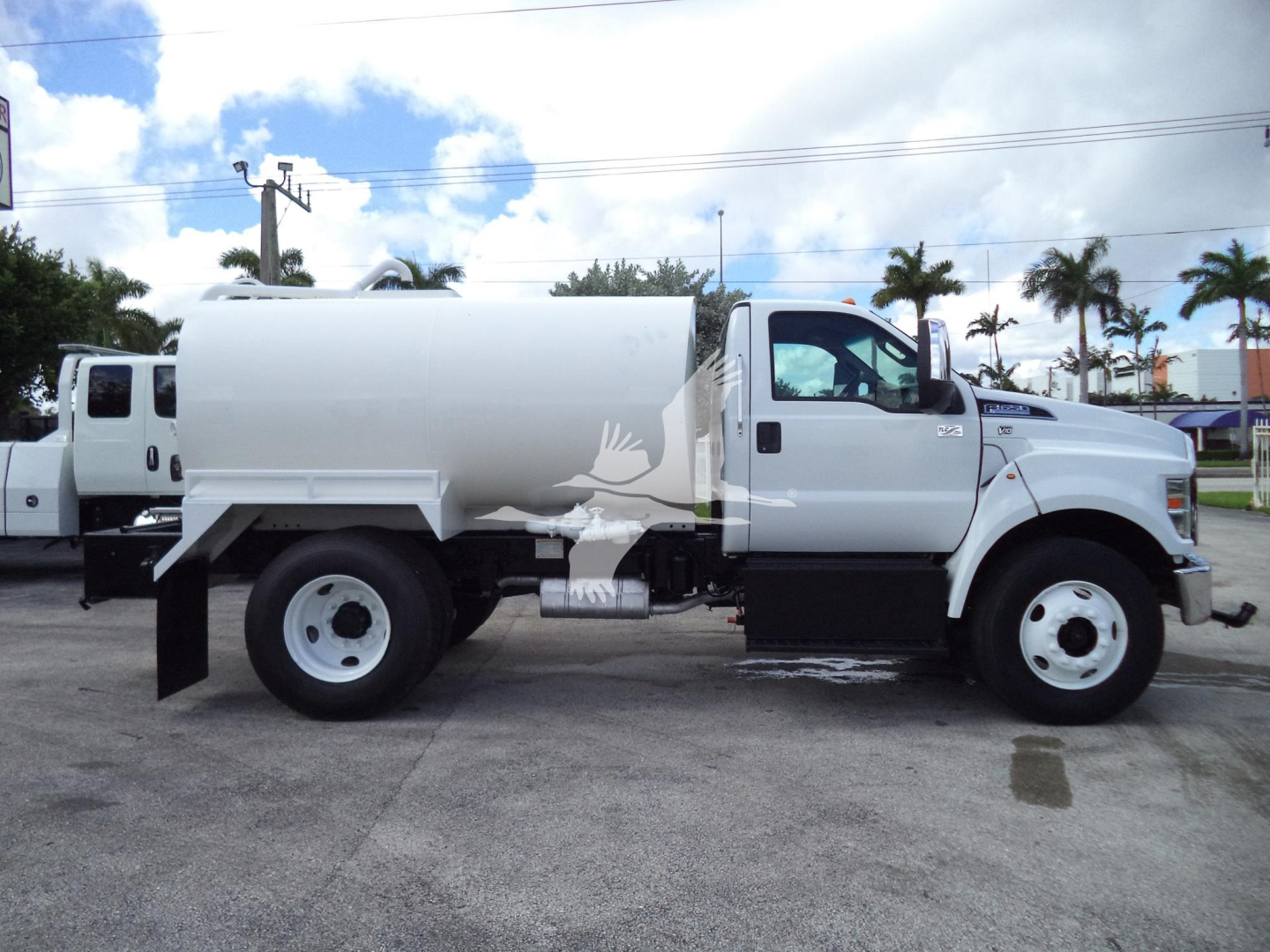 Side view of a white 2017 Ford F-650 SD truck with a large cylindrical tank, black bumper steps, and dual rear wheels.