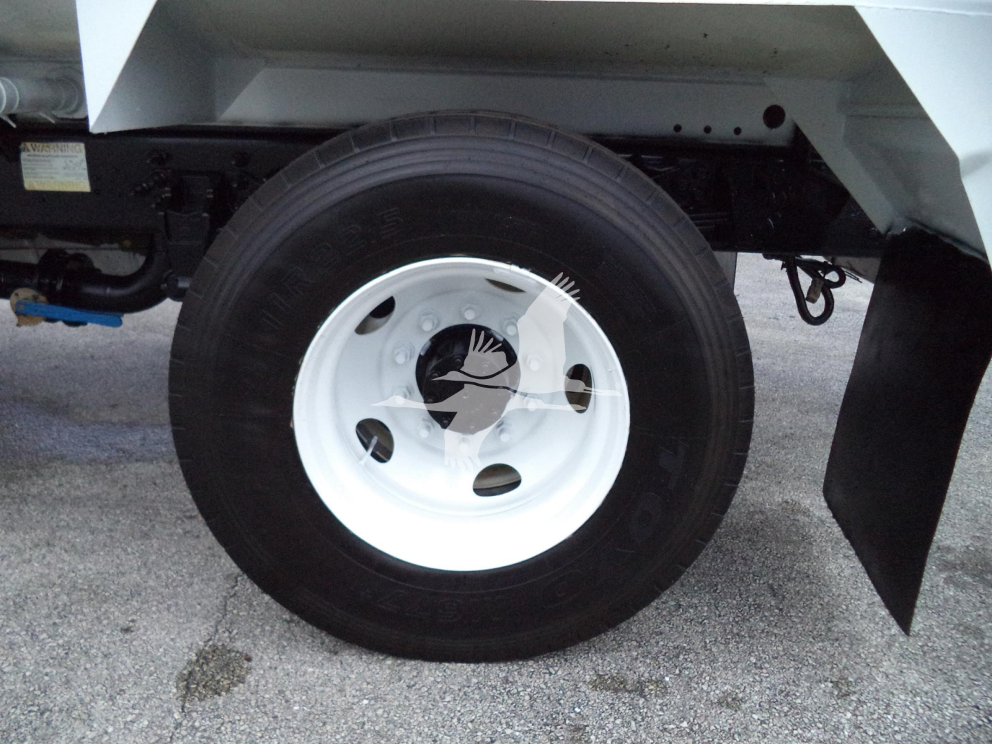 Wheel and undercarriage of a 2017 Ford F650 Sd truck showing a white steel wheel and black tire; partial undercarriage and mudflap visible.