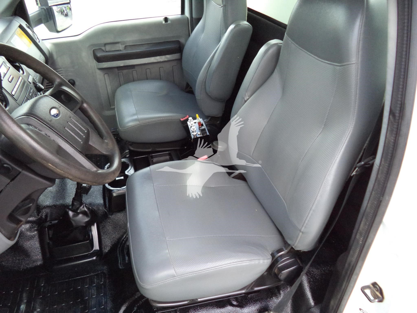 Truck cabin interior showing front seats and steering wheel of a used 2017 Ford F650. Gray cloth seats, black steering wheel, center console, and door panel visible.