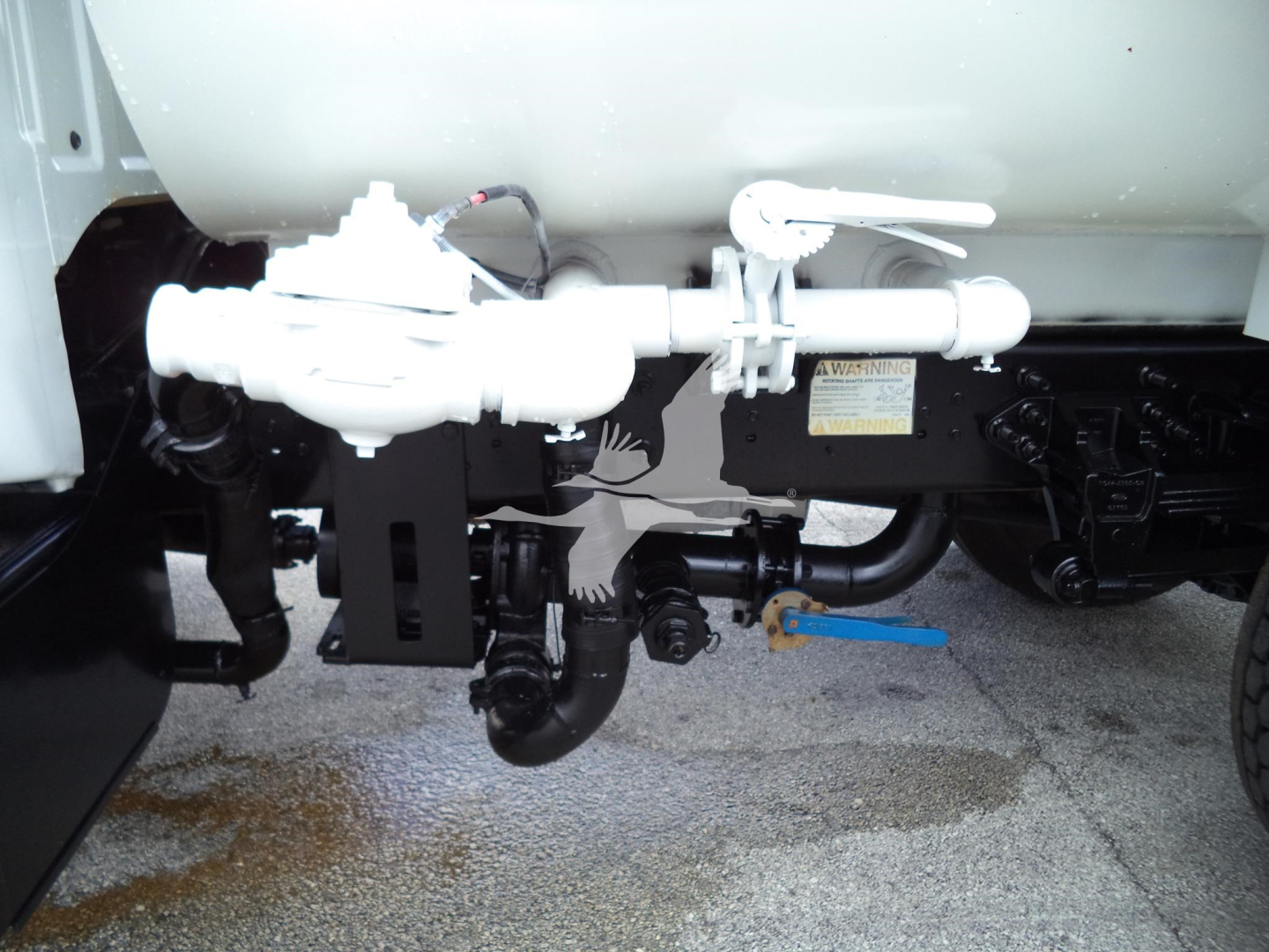 Component view showing fuel or hydraulic line assembly under a truck with a white valve and blue handle.