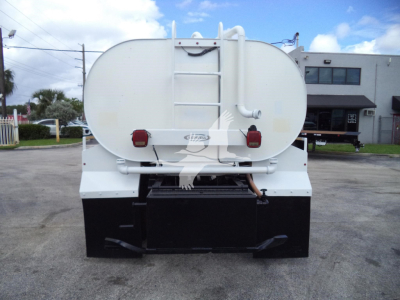 Back view of a white Ford F650 truck with a large circular tank, ladder, rear lights, and black underride/box bumper.