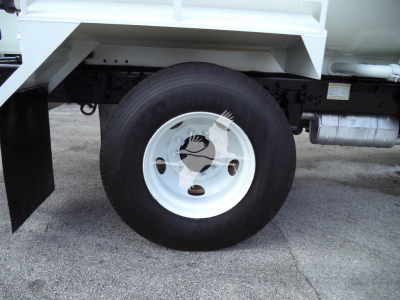 Truck wheel and rear suspension of a Ford F650 SD truck showing a white steel wheel with black tire and a large fuel tank behind.