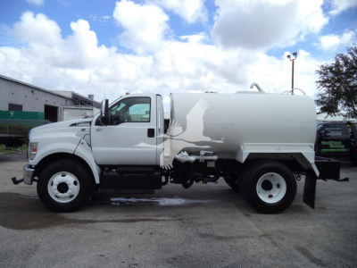 Ford F650 water truck side view showing tank and cab with white and gray livery.