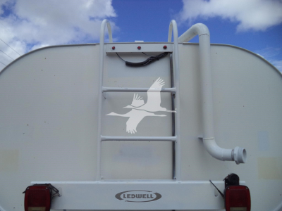 Rear view of a white tank truck with a ladder, railings, and a curved exhaust pipe. A LeDwell logo is visible on the frame under the tank.