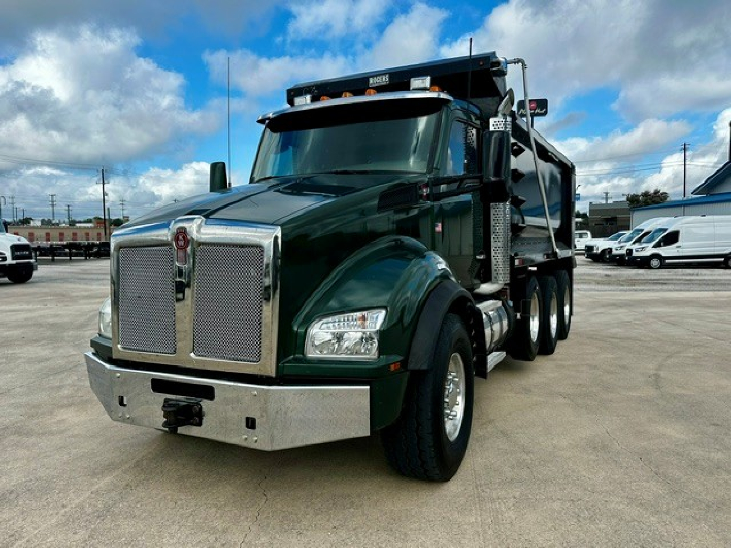 Kenworth T880 dump truck in dark green showing front grille, bumper, and dual rear axles.