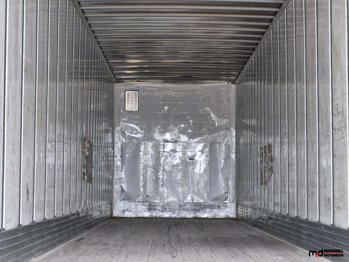 Trailer interior showing metal walls, worn floor, and a rear wall with a vent at left; utility 53' dry van trailer interior view