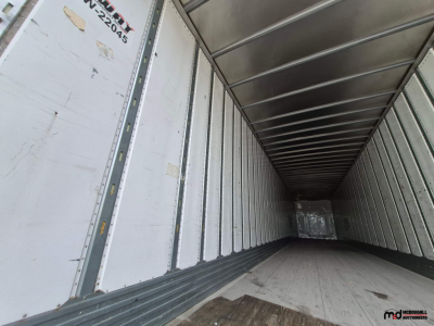 Inside view of a 53' dry van trailer cargo area with metal sidewalls and a wooden floor; partial VIN tag and numbers on left door.