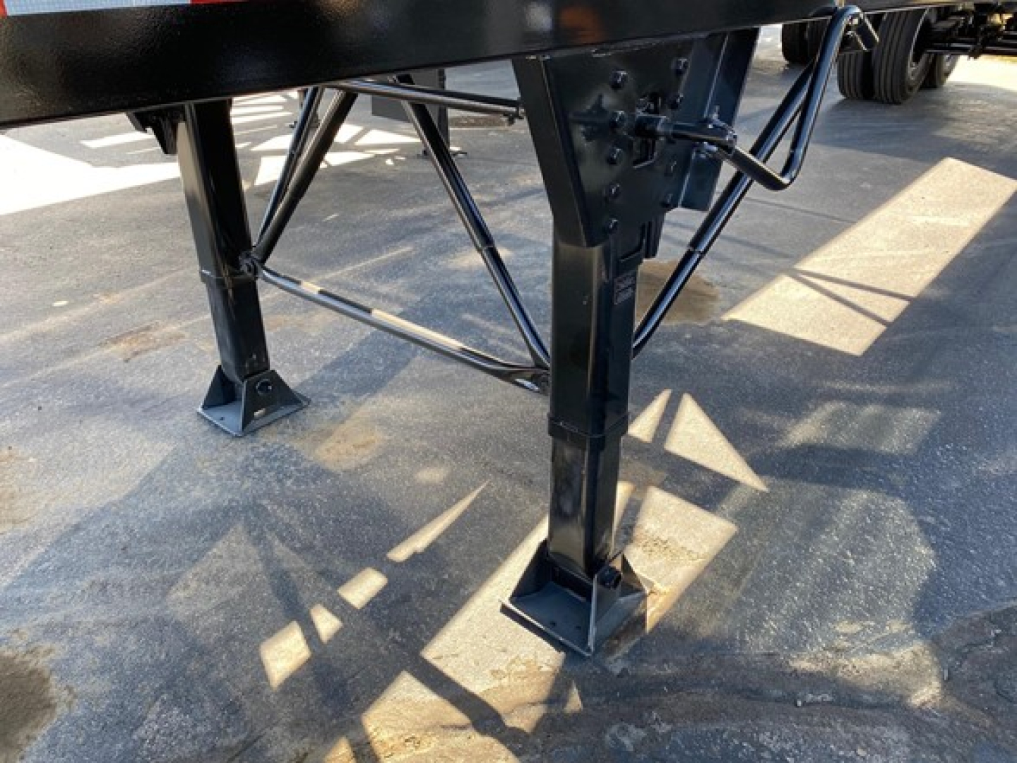 Trailer leg and support framework of a dump trailer showing metal legs, brackets, and cross-bracing.