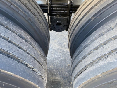 Trailer suspension showing dual tires with a central mounting point and suspension linkage on a dump trailer.