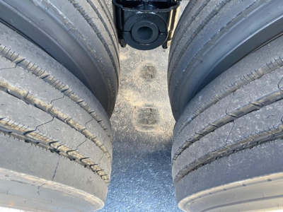 Truck trailer dual rear tires and chassis crossmember showing treaded tires and central hitch area.