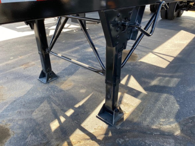 Trailer leg and support framework of a dump trailer showing metal legs, brackets, and cross-bracing.