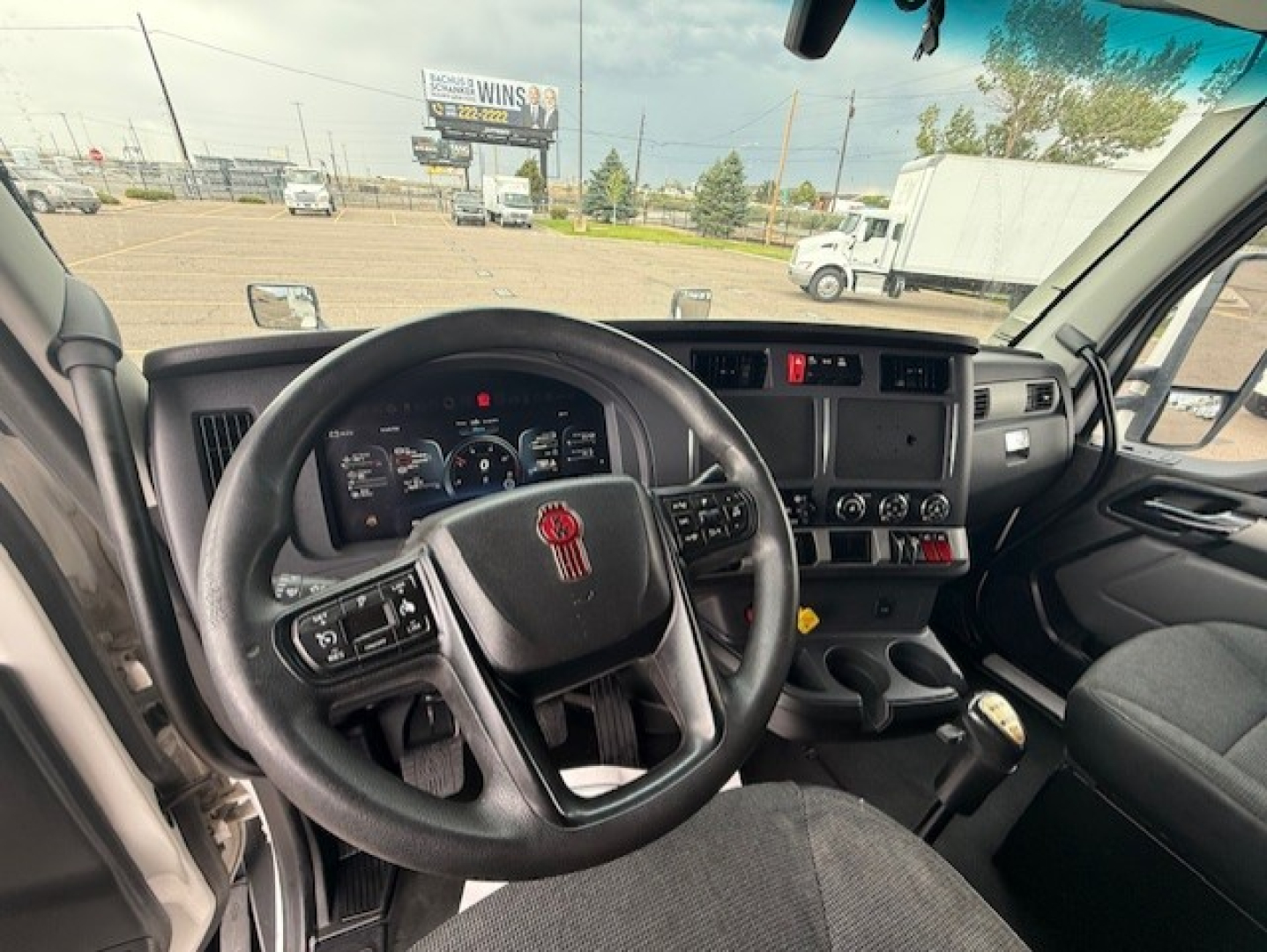 Kenworth T680 cockpit showing steering wheel, dashboard, and gear shift in a sleeper cab.