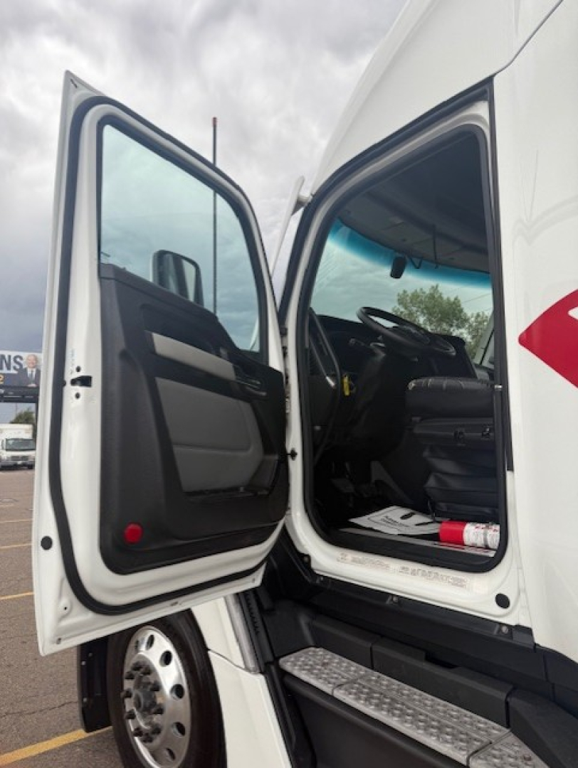 Kenworth T680 cab exterior with open driver door showing interior seating and steps.