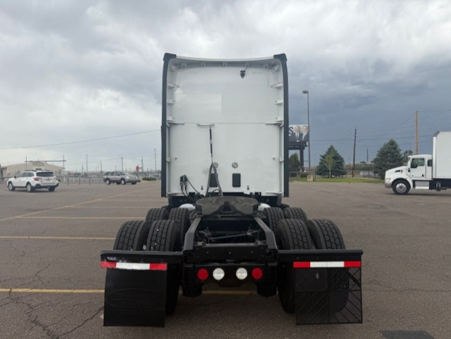 Kenworth T680 rear view showing fifth wheel, dual rear axles, and mud flaps in a dealership lot.