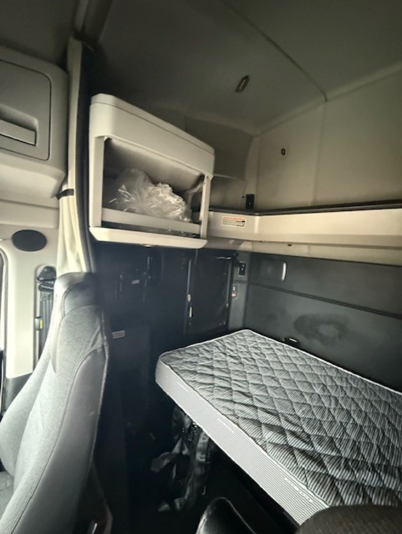 Kenworth T680 sleeper cab interior showing upper storage cabinet and bunk bed with mattress.