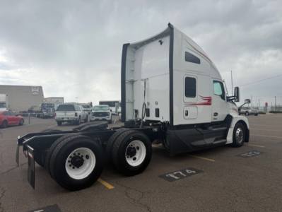 Kenworth T680 cab with sleeper in a parking lot, side view showing dual rear axles and white wheels
