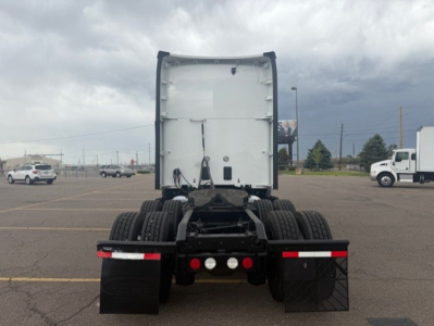 Kenworth T680 rear view showing fifth wheel, dual rear axles, and mud flaps in a dealership lot.
