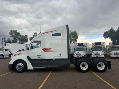Kenworth T680 tractor cab side view showing sleeper, white with red graphics, 6x4 rear truck configuration, multiple trailers in background.