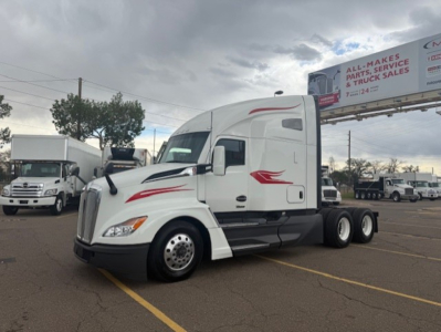 Kenworth T680 tractor in a parking lot, side view showing sleeper cab and dual rear axles.