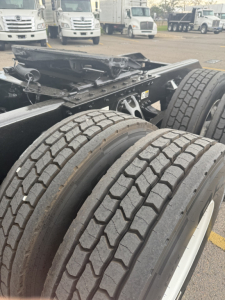 Kenworth truck chassis with dual rear tires and undercarriage view showing frame and suspension components.