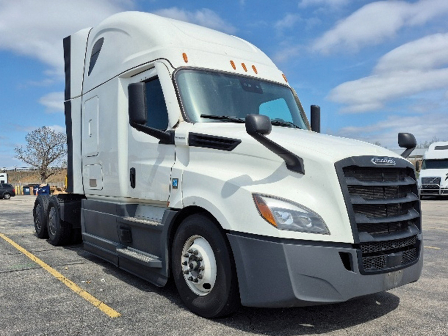 Freightliner Cascadia 126 heavy truck front-right view showing cab, grille, headlights, and side mirror in a parking lot.