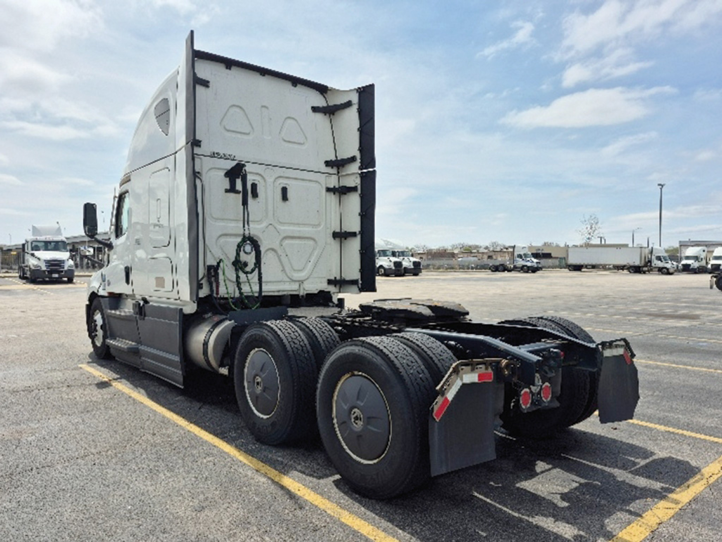 Rear/side view of a Freightliner Cascadia 126 truck tractor chassis showing fifth wheel, rear triple axle, and sleeper cabin with rounded door.