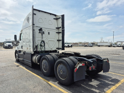 Rear/side view of a Freightliner Cascadia 126 truck tractor chassis showing fifth wheel, rear triple axle, and sleeper cabin with rounded door.