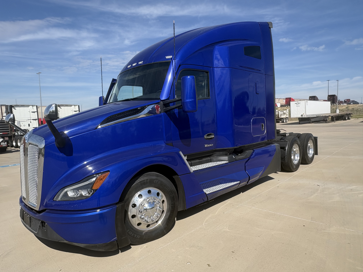 Kenworth T680 in blue, side view showing sleeper cab and dual rear axles.