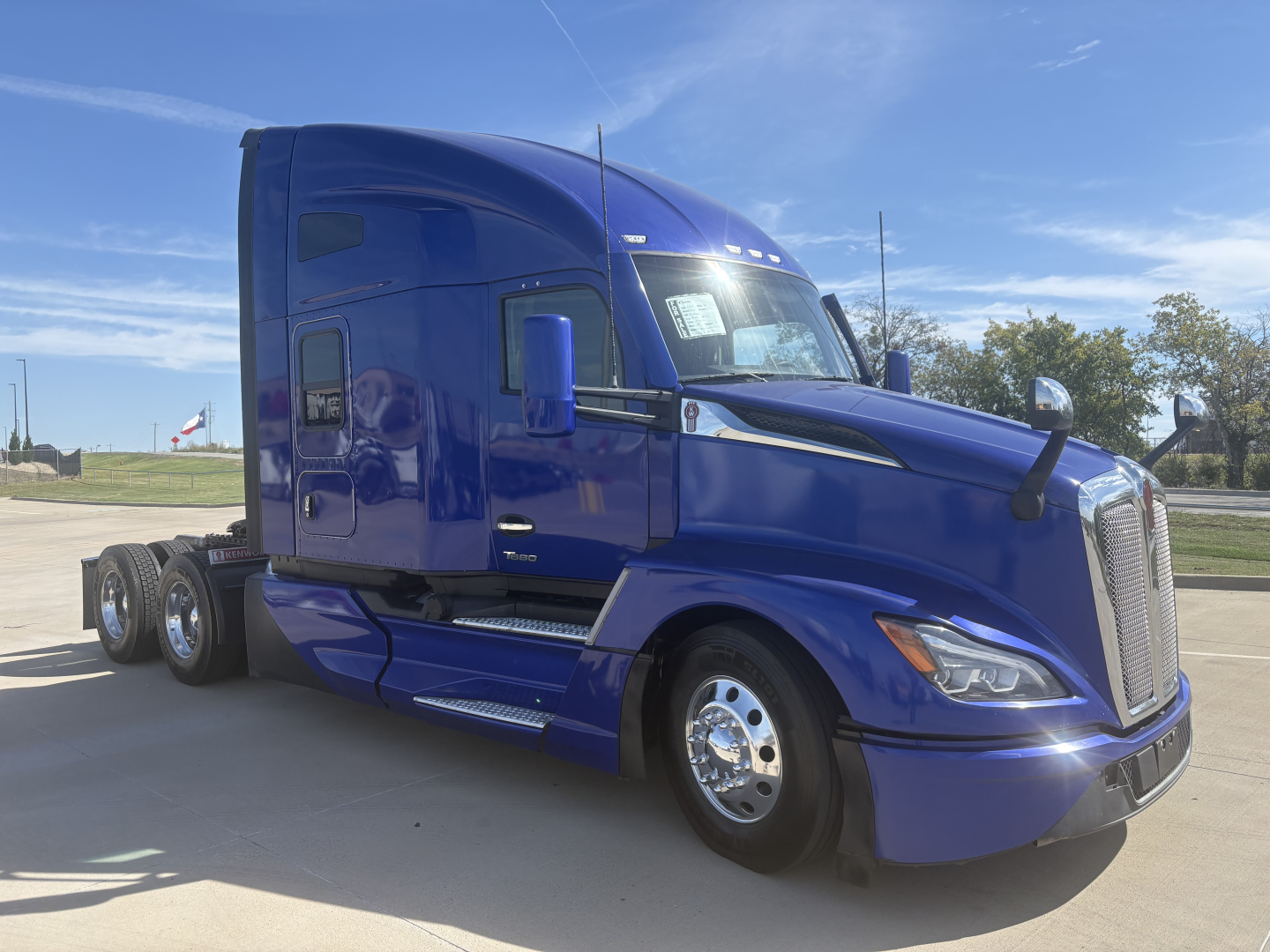 Kenworth T680 blue semi-truck in factory-new paint with sleeper cab, side view showing front grille, headlights, and chrome wheels.