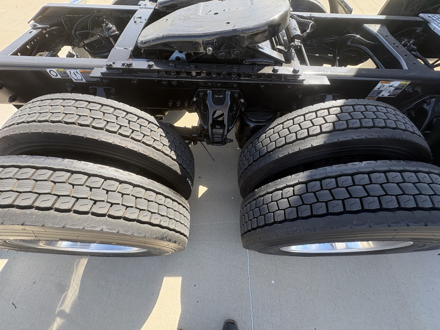Kenworth T680 chassis and dual rear tires view showing part of the frame and wheel hubs.