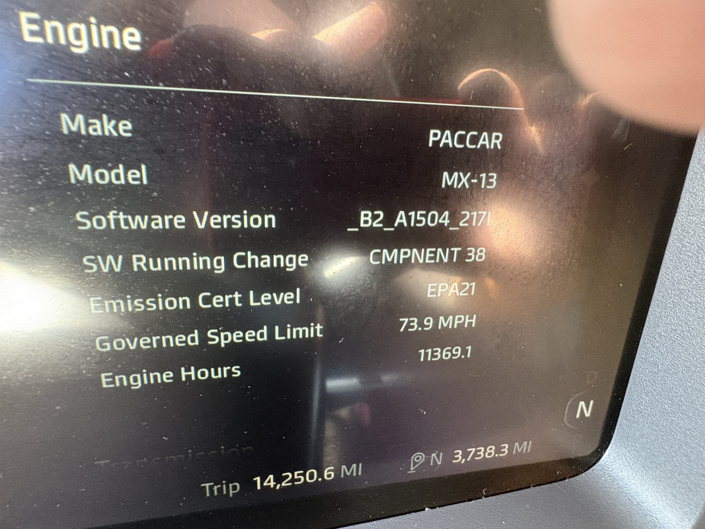 Truck cab display showing Engine make PACCAR, model MX-13, software version B2_A1504_217, CMPNENT 38, emission cert EPA21, speed limit 73.9 MPH, engine hours 11369.1, trip 14,250.6 mi, odometer 3,738.3 mi.