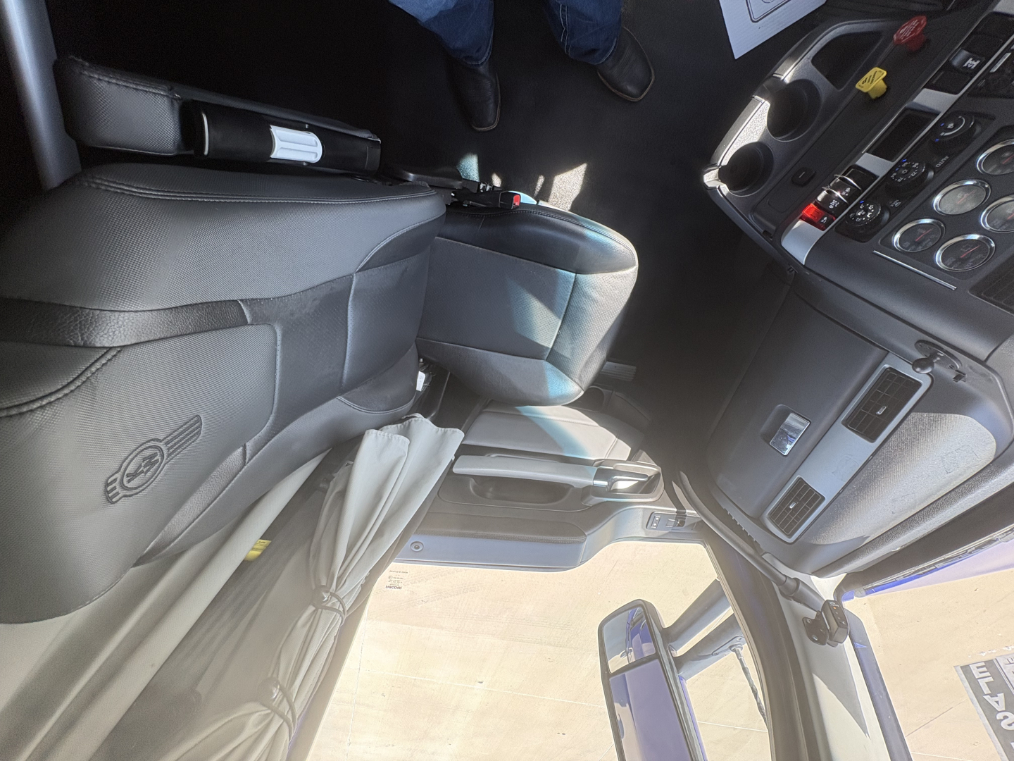 Kenworth T680 interior cab view showing dashboard and seat area with steering wheel and controls.