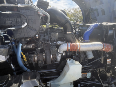 Kenworth T680 engine bay showing intake piping, hoses, and coolant reservoir.