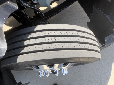 Kenworth T680 wheel and dual rear axle area showing tire tread near chrome lug nuts and hubcap.