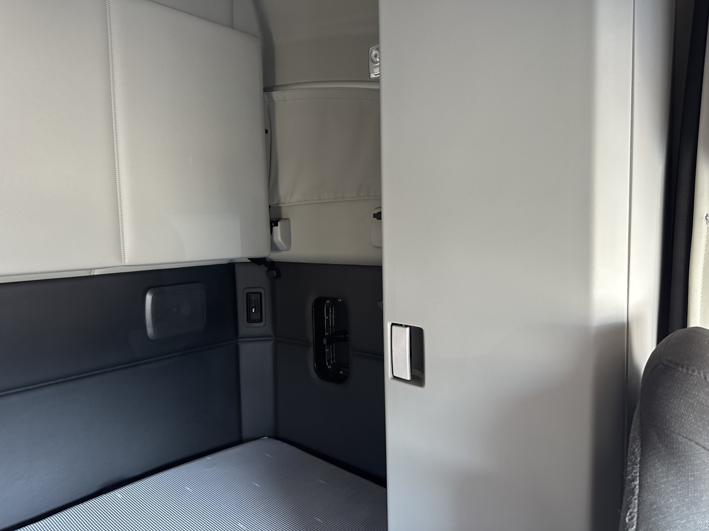 Kenworth T680 cab interior showing sleeper area and storage compartments.