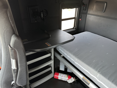 Kenworth T680 cabin interior showing sleeper bed and storage cabinet with table, 2023 model year.