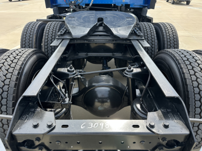 Kenworth truck chassis view showing rear section with dual rear axles and suspension, frame rails, third axle, and differential housing.
