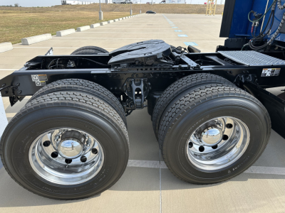 Kenworth T680 coupling area showing dual rear axle with large dual tires and polished chrome wheels, frame and fifth wheel kingpin visible.