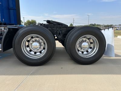 Kenworth T680 truck dual rear wheels showing chrome rims and tires with chassis frame and fuel/air lines visible.