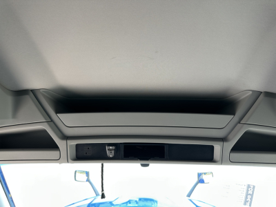 Cab interior of a Kenworth truck with overhead console and sun visors visible.