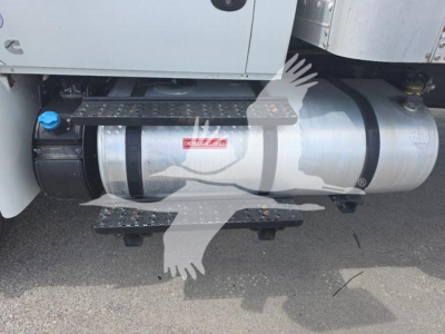 Truck side view showing diesel fuel tank and side step on International MV, blue fill cap, under-cab storage, and metal chassis.
