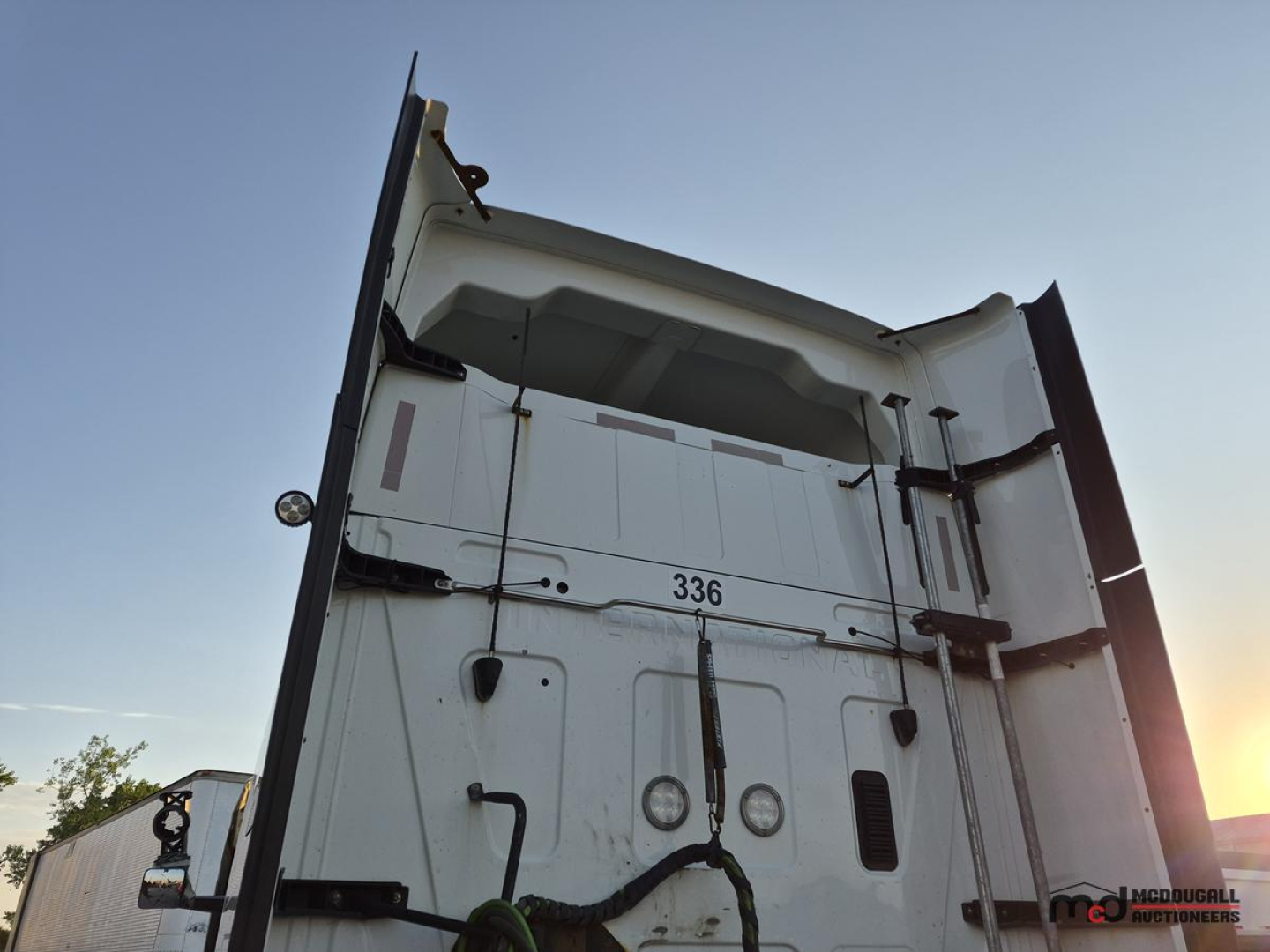Truck bed rear view with vertical doors and hydraulic latches; white surface with a '336' marking and various circular access ports.