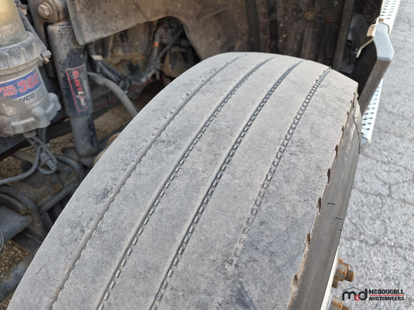 Truck front wheel/view showing tire tread and undercarriage components in service condition.