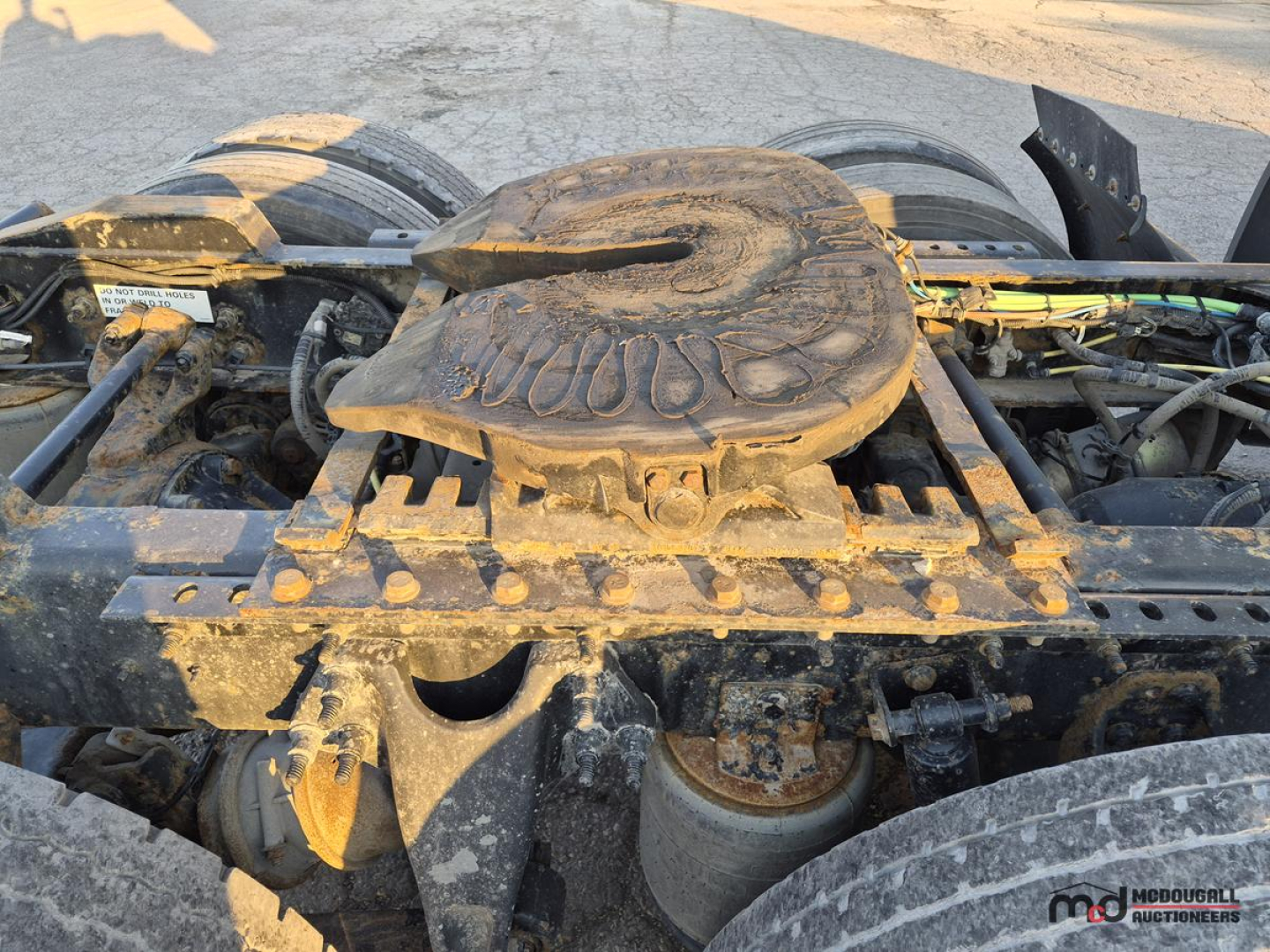 Truck engine bay showing air reservoir and fifth wheel on a 2021 International LT625 T/A Sleeper with dirt and grime.
