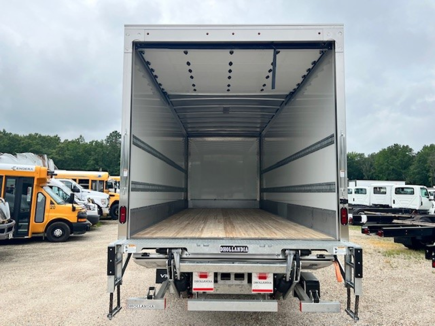 Box truck cargo area of a 2025 Mack MD6 with empty interior and wooden floor, open rear doors, viewed from the back.