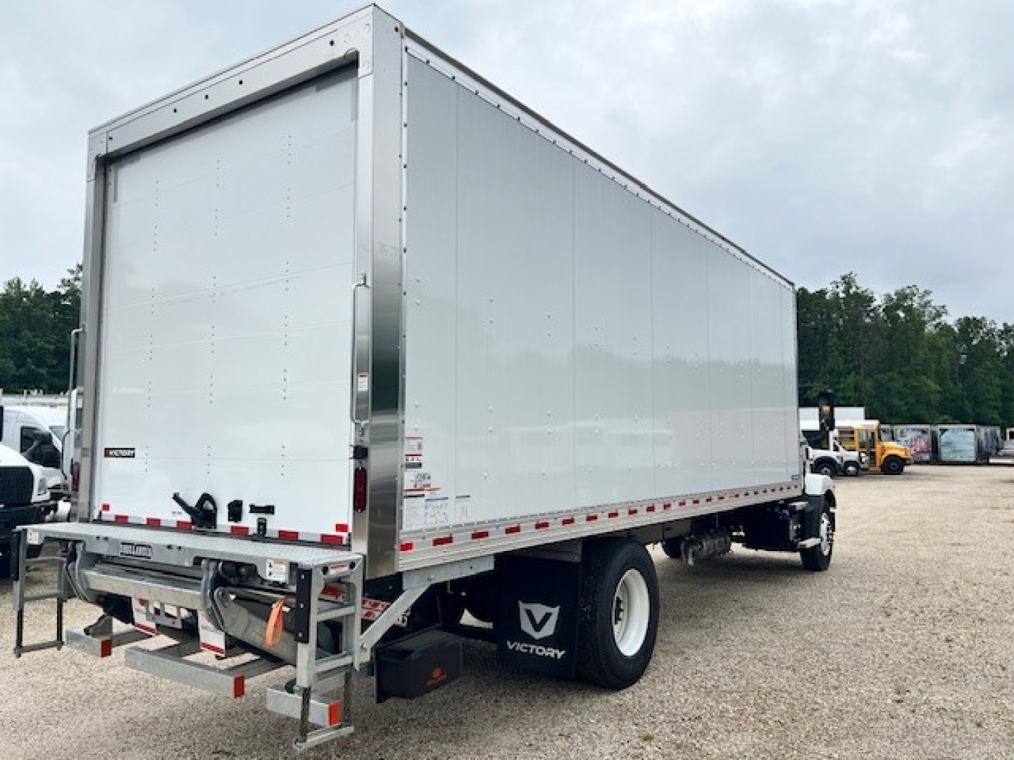 Box truck rear-left view showing cargo box and rear bumper with reflective tape and Victory mudflap.