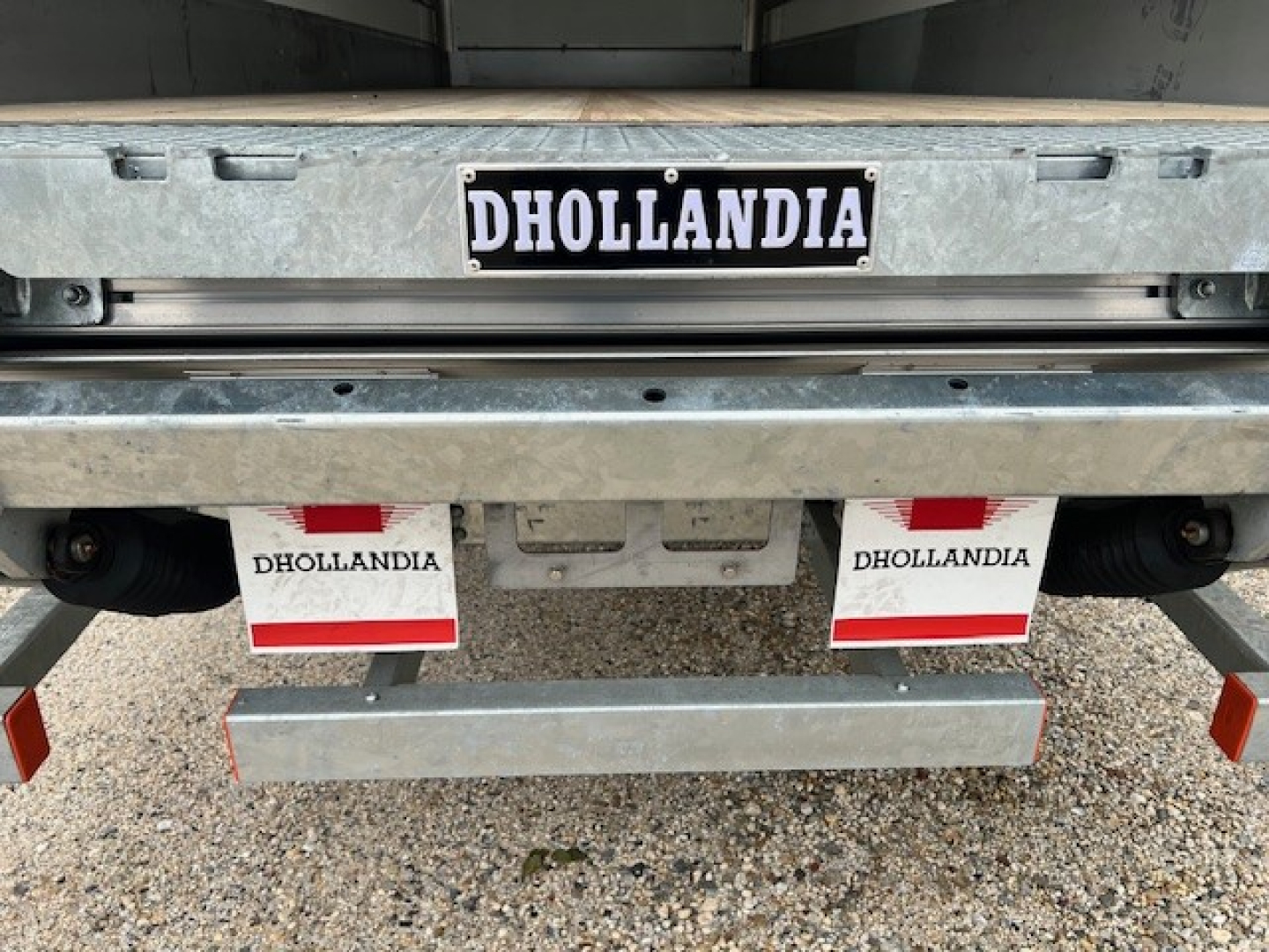 Rear view of a Mack MD6 truck showing Dhollandia tailgate license plate and hydraulic lift hardware, with Dhollandia branding on mudflaps and bumper.