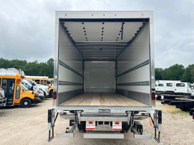 Box truck cargo area of a 2025 Mack MD6 with empty interior and wooden floor, open rear doors, viewed from the back.
