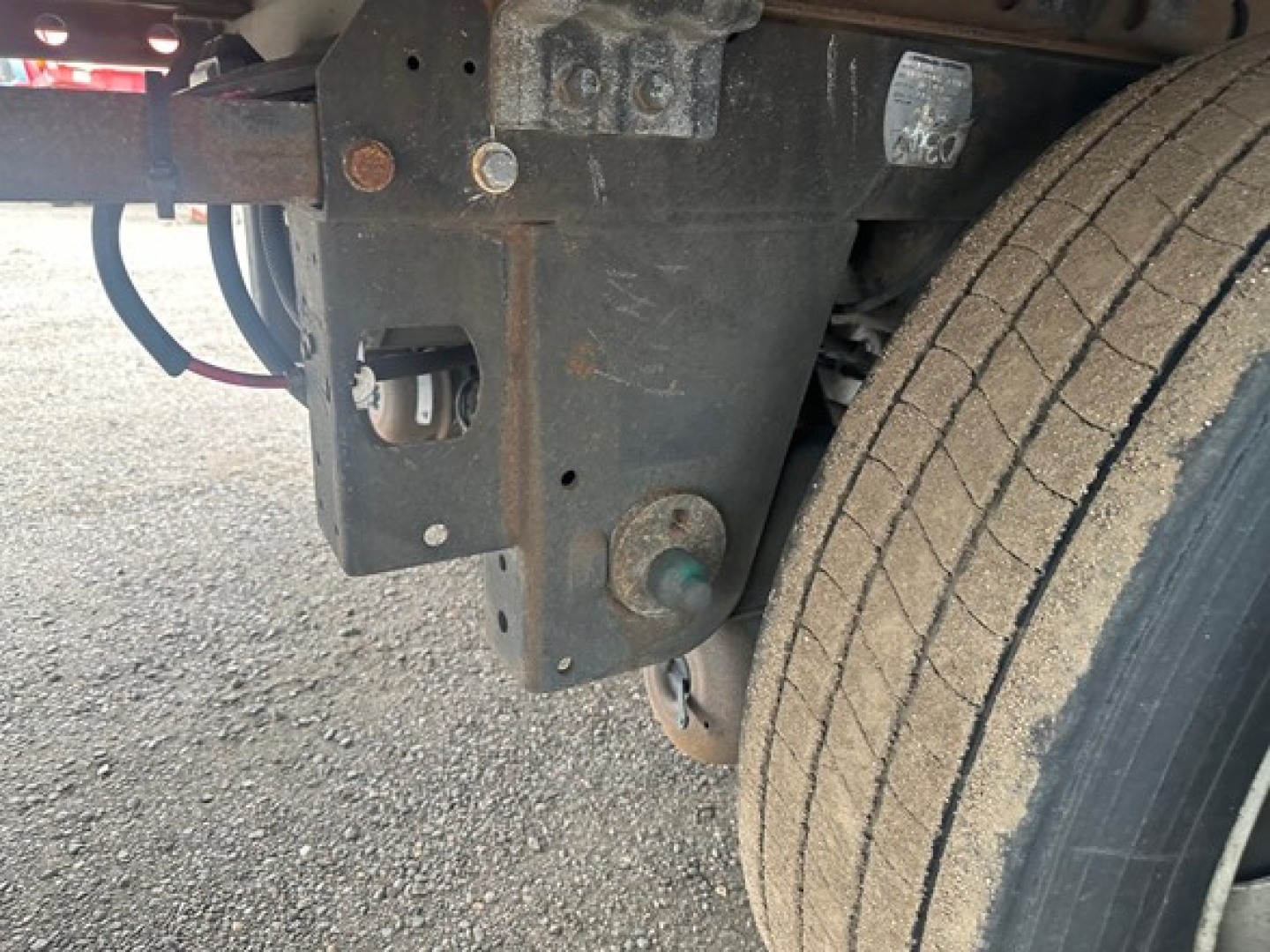 Trailer hitch area showing metal frame and rear suspension with a large tire, toungue welded bracket, and electrical wiring harness visible.